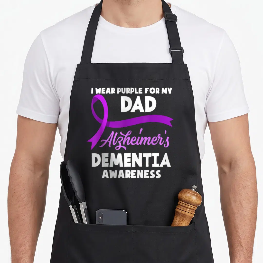 Dementia awareness alzheimer's aprons - Purple ribbon overlapping white text I WEAR PURPLE FOR MY DAD Alzheimer's — shown on a black cotton canvas apron against a white background