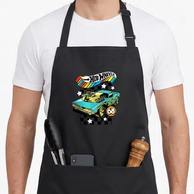 Retro wheel apron - Light blue muscle car on checkerboard with Hot Wheels logo and orange 68 circle — shown on a black cotton canvas apron against a white background