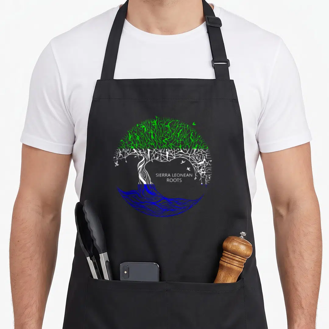 Leonean sierra apron - Circular tree with green canopy holding people, white trunk with birds, blue water roots — shown on a black cotton canvas apron against a white background