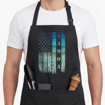 Samoa american flag apron - US flag shape filled with ocean image, vertical white SAMOA letters, distressed blue teal — shown on a black cotton canvas apron against a white background