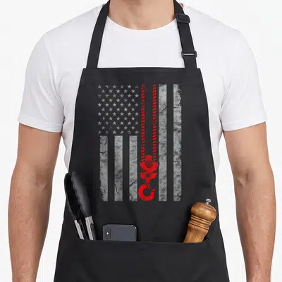 Operator american flag apron - Distressed white USA flag with vertical red crane chain and hook superimposed — shown on a black cotton canvas apron against a white background