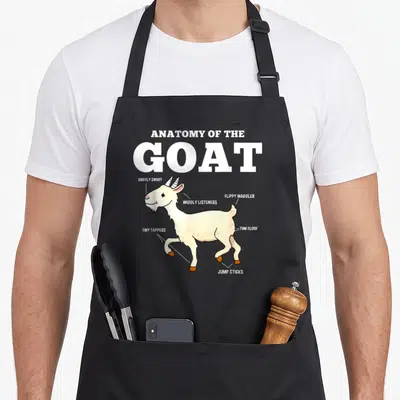 Funny goat anatomy apron - Cartoon goat diagram with labels Sniffly Snoot, Wiggly Listeners, and Jump Sticks — shown on a black cotton canvas apron against a white background