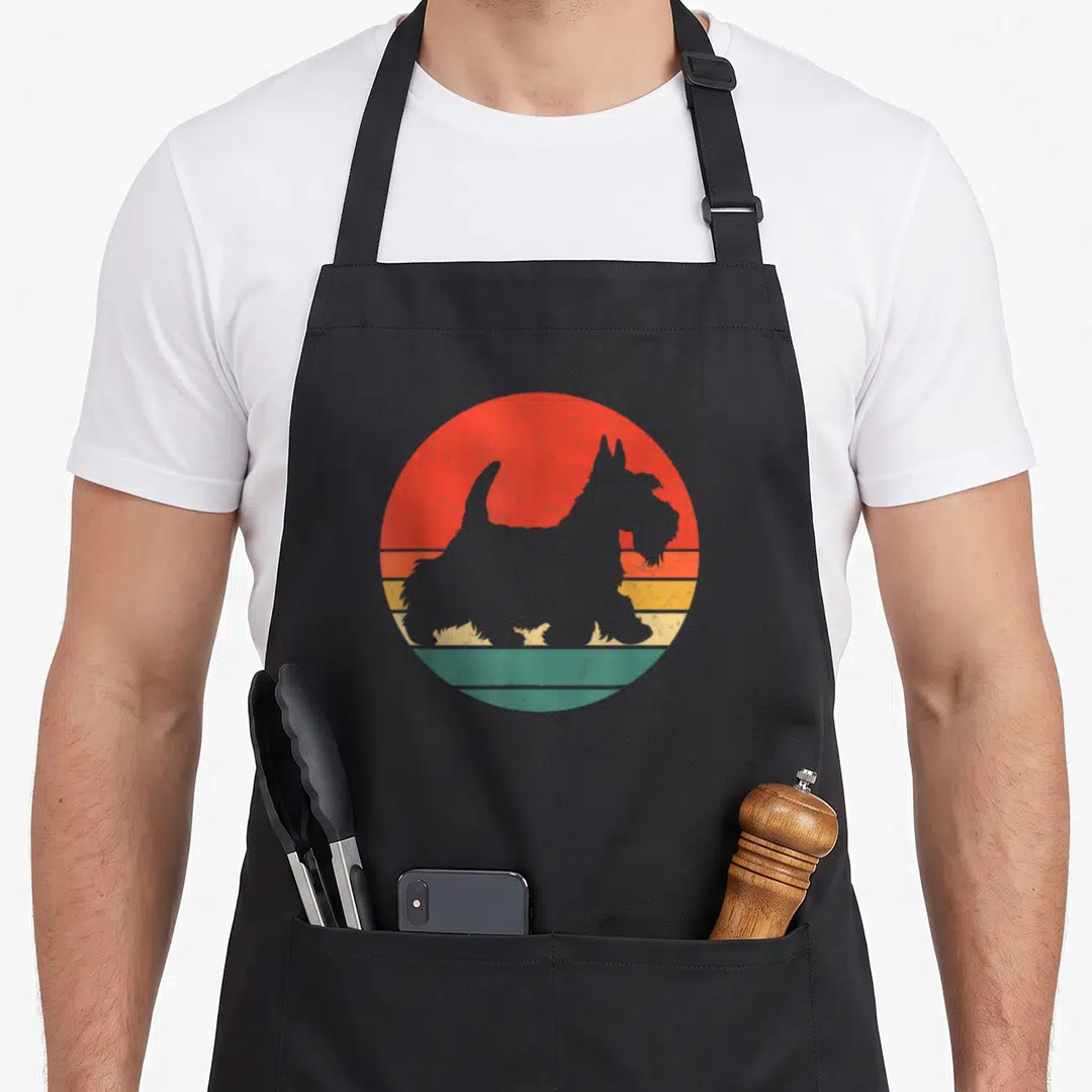 Terrier silhouette dog apron - Grey Scottish Terrier silhouette against red orange yellow and green striped circle — shown on a black cotton canvas apron against a white background