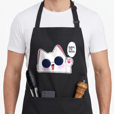 Nah cat apron - White cartoon cat with dark glasses and pink details saying NAH, I'D WIN — shown on a black cotton canvas apron against a white background