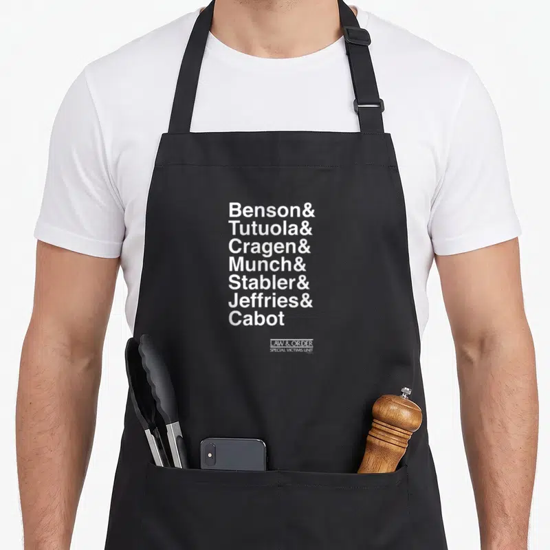 Law ampersand apron - Stacked white text listing Benson, Tutuola, Cragen, Munch, Stabler, Jeffries, and Cabot with SVU — shown on a black cotton canvas apron against a white background