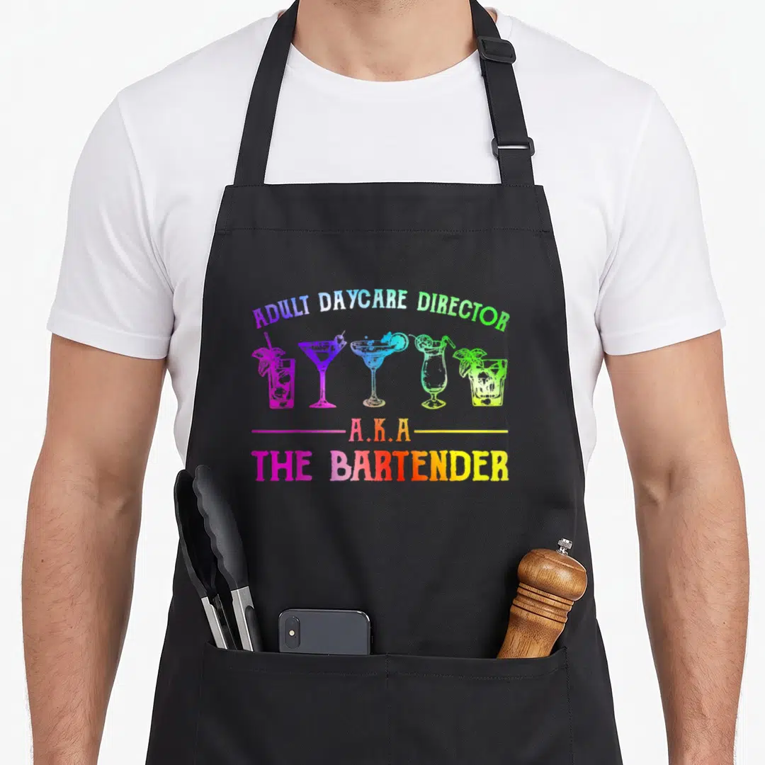 Director bartender apron - ADULT DAYCARE DIRECTOR A.K.A THE BARTENDER text over five colorful cocktail glasses — shown on a black cotton canvas apron against a white background