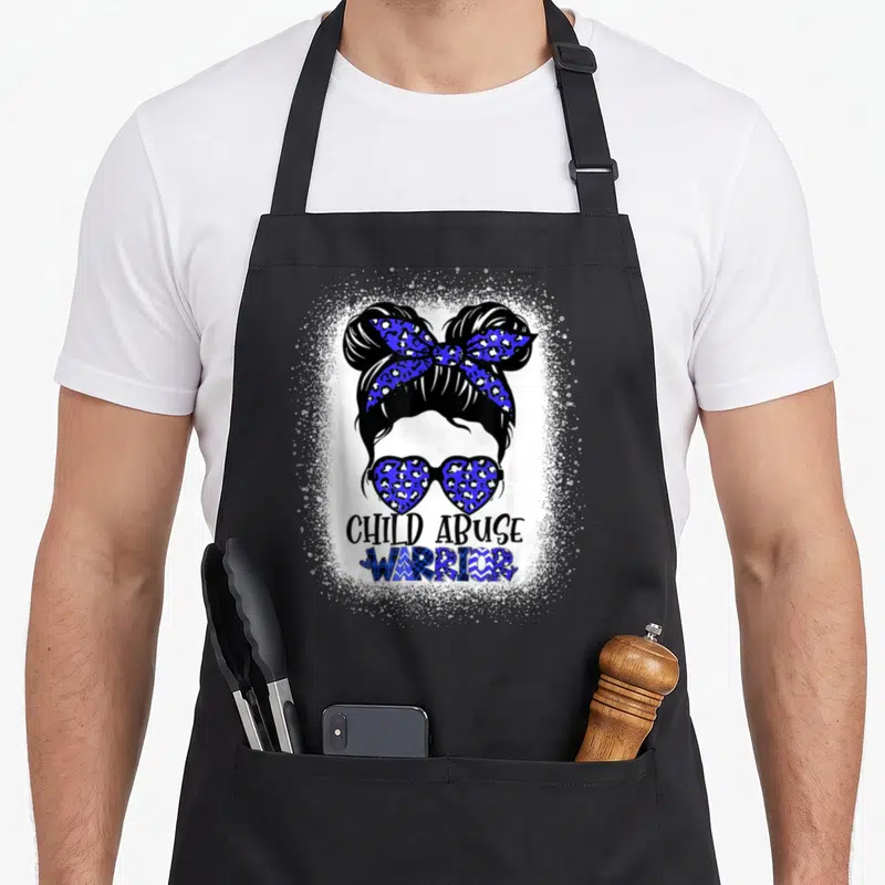 Warrior child abuse prevention apron - Woman head with two buns, blue leopard heart sunglasses, and text CHILD ABUSE — shown on a black cotton canvas apron against a white background