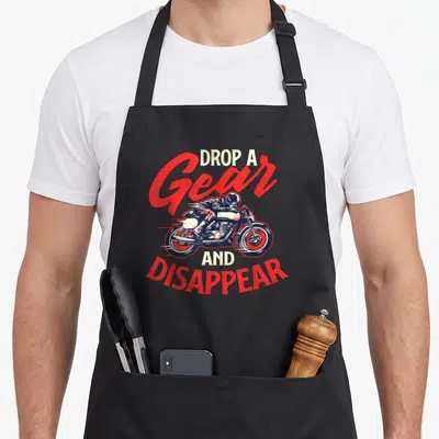 Drop motorcycle aprons - Distressed red and white text reading DROP A Gear AND DISAPPEAR around a biker illustration — shown on a black cotton canvas apron against a white background