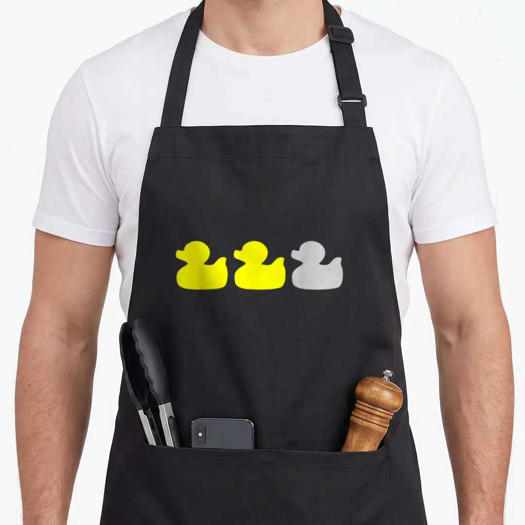 Cute duck minnesota apron - Three rubber ducks in yellow and grey arranged horizontally on grey background — shown on a black cotton canvas apron against a white background