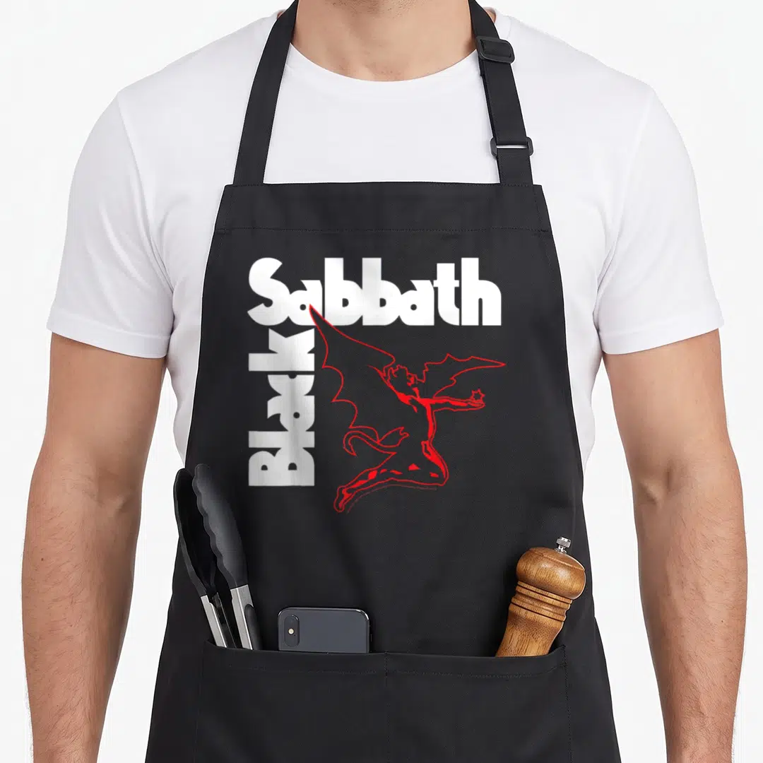 Creature black sabbath apron - White Sabbath text, vertical Black text, red winged devil holding a star — shown on a black cotton canvas apron against a white background