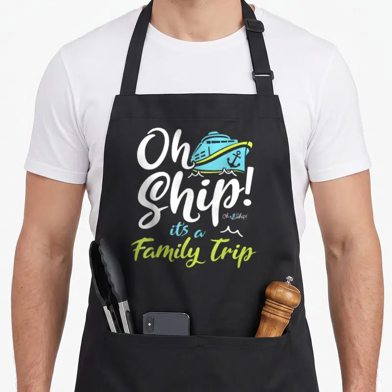 Ship trip family aprons - Oh Ship It's a Family Trip text with cartoon blue cruise ship and lime green waves — shown on a black cotton canvas apron against a white background