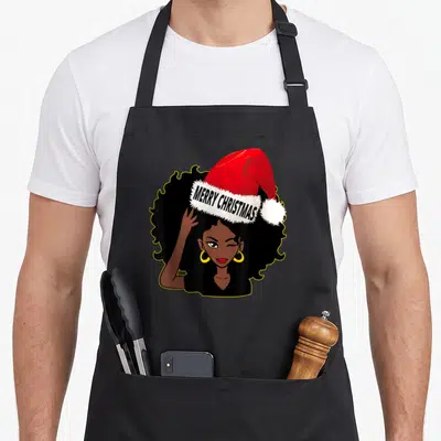 Afro merry christmas apron - Cartoon woman winking wearing red santa hat with MERRY CHRISTMAS text on white trim — shown on a black cotton canvas apron against a white background