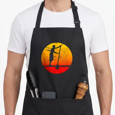 Surf stand up paddle apron - Grey paddler silhouette inside yellow orange red gradient circle — shown on a black cotton canvas apron against a white background