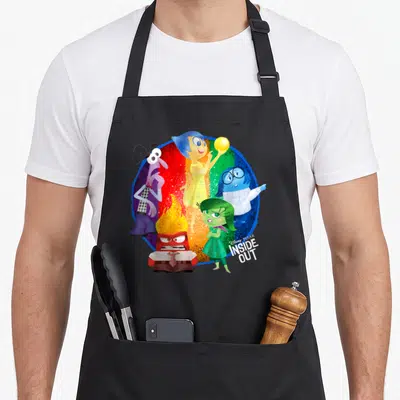 Circle colorful apron - Five cartoon emotions in yellow blue red green purple on rainbow circle with logo — shown on a black cotton canvas apron against a white background