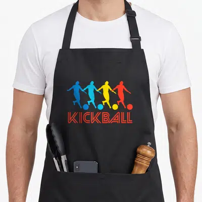 Pop kickball apron - Four colorful player silhouettes holding hands above red KICKBALL text — shown on a black cotton canvas apron against a white background