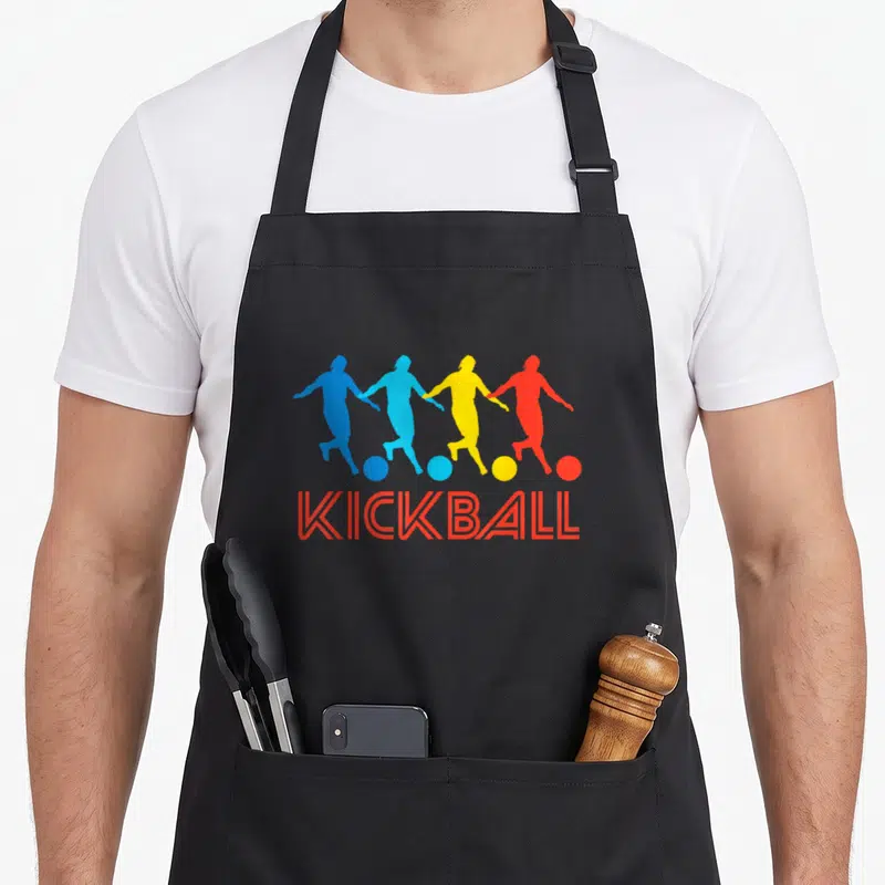 Pop kickball apron - Four colorful player silhouettes holding hands above red KICKBALL text — shown on a black cotton canvas apron against a white background