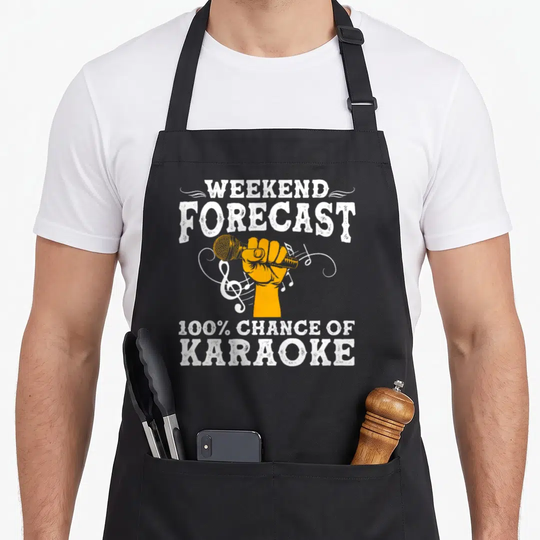 Karaoke box apron - Distressed white text Weekend Forecast 100% Chance of Karaoke above orange hand holding microphone — shown on a black cotton canvas apron against a white background
