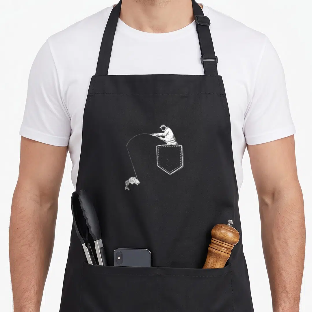 Fisherman father fishing apron - White distressed fisherman in shield holding rod catching jumping fish on black bib — shown on a black cotton canvas apron against a white background