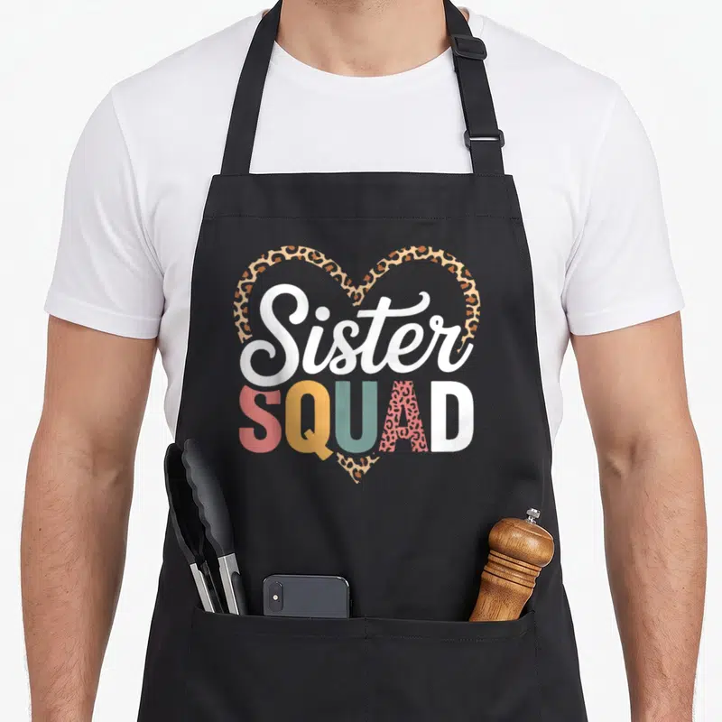 Squad sister finally apron - Sister SQUAD text over leopard heart in red yellow teal tan brown and white — shown on a black cotton canvas apron against a white background