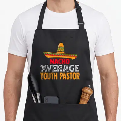 Youth mexican apron - Sombrero graphic above stacked text reading Nacho Average Youth Pastor in red, white, and orange — shown on a black cotton canvas apron against a white background