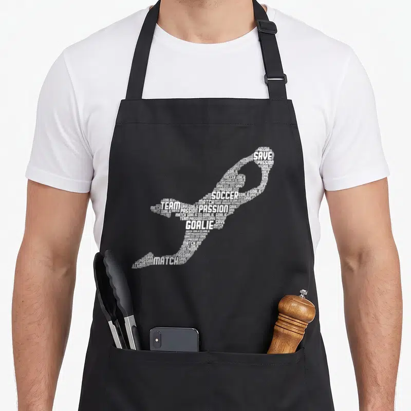 Soccer goalkeeper goalie apron - White typography forming a soccer shoe shape with words SOCCER GOALIE SAVE TEAM — shown on a black cotton canvas apron against a white background
