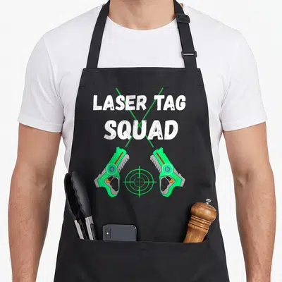 Squad tag apron - LASER TAG SQUAD text above two green guns and crosshair — shown on a black cotton canvas apron against a white background