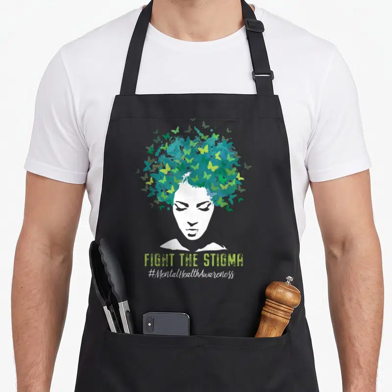 Stigma mental health awareness apron - White woman silhouette with blue teal lime green butterfly hair and FIGHT — shown on a black cotton canvas apron against a white background