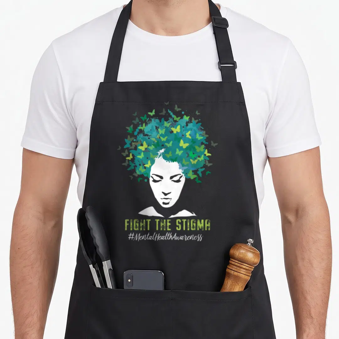 Stigma mental health awareness apron - White woman silhouette with blue teal lime green butterfly hair and FIGHT — shown on a black cotton canvas apron against a white background