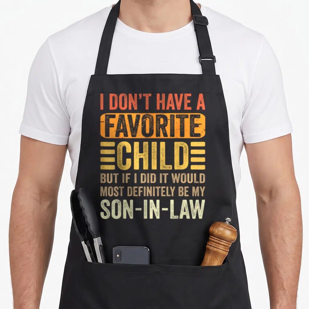 Most child apron - Stacked typography text in red orange yellow beige and white with distressed finish — shown on a black cotton canvas apron against a white background