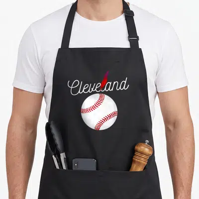 Cleveland baseball apron - White script Cleveland text with red feather and baseball graphic on black fabric — shown on a black cotton canvas apron against a white background