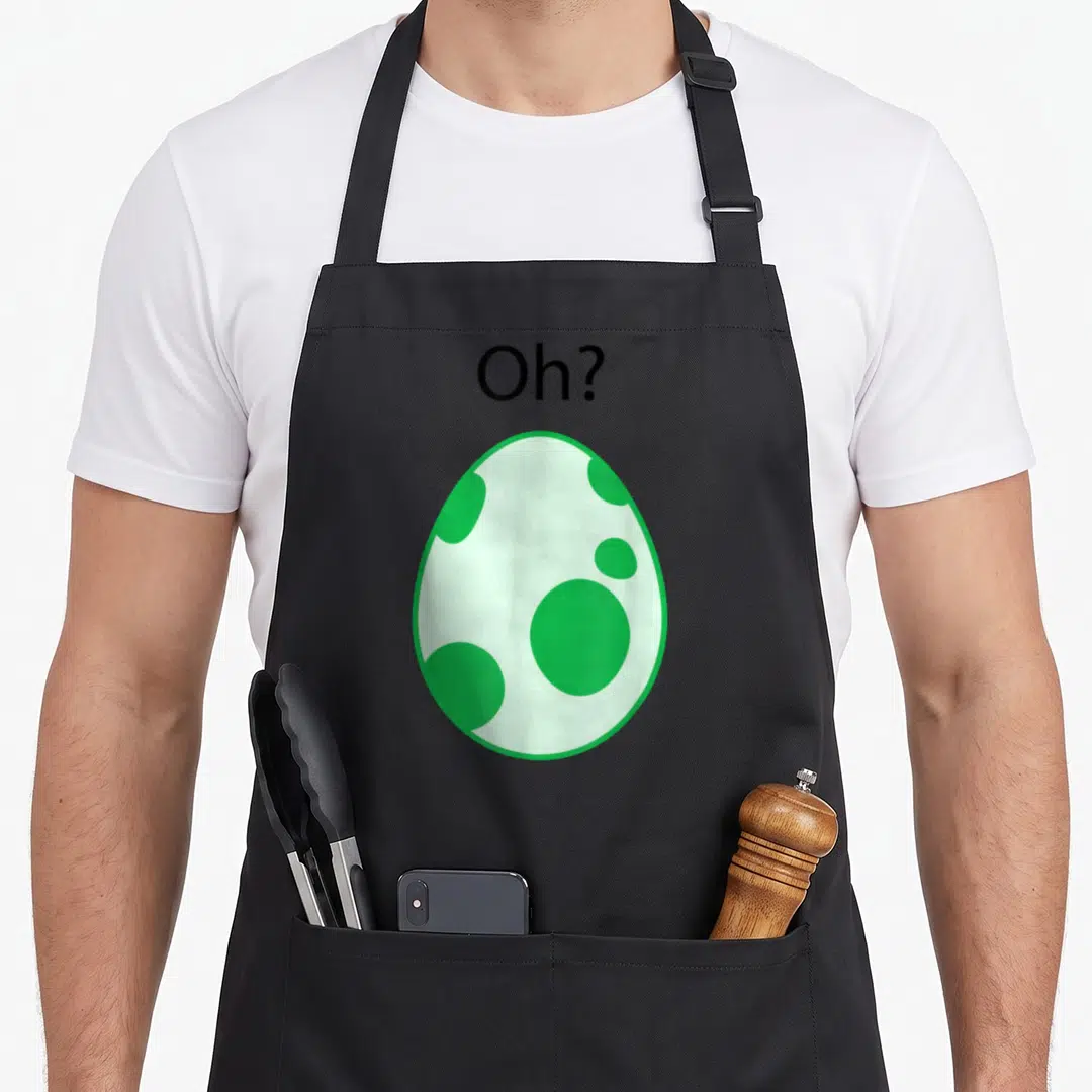 Gamer egg apron - Spotted green egg with Oh? text above in cartoon style — shown on a black cotton canvas apron against a white background