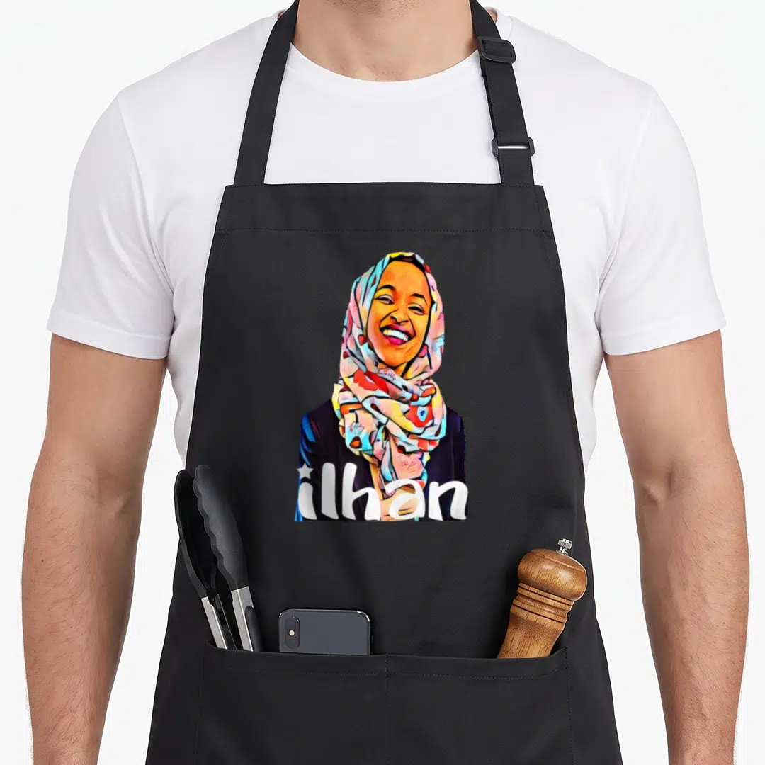 Ilhan political aprons - Cartoon woman in patterned hijab with ilhan text in white, blue, red, yellow — shown on a black cotton canvas apron against a white background