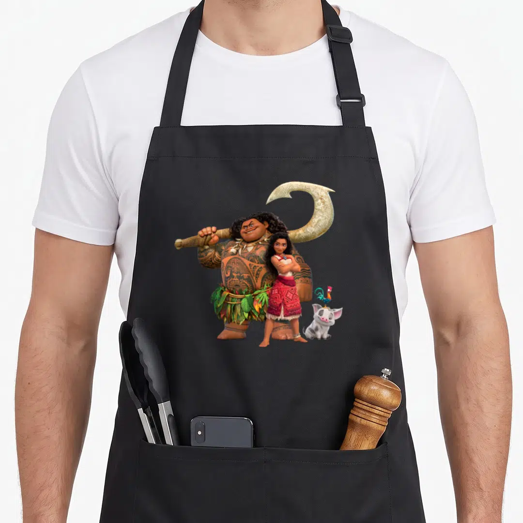 Pua novelty apron - Maui holding fishhook behind Moana with Pua pig and Heihei rooster in cartoon style — shown on a black cotton canvas apron against a white background
