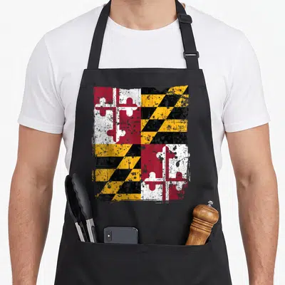 State maryland eastern apron - Distressed square flag pattern in red white yellow and black with splattered texture — shown on a black cotton canvas apron against a white background