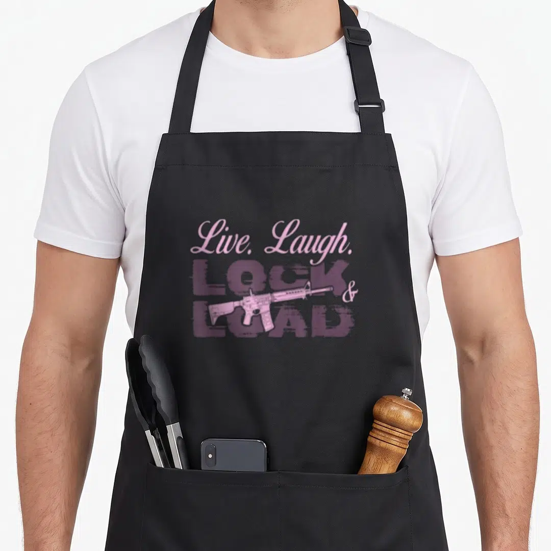 Live gun apron - Pink script text and purple distressed block letters with a rifle graphic overlay — shown on a black cotton canvas apron against a white background