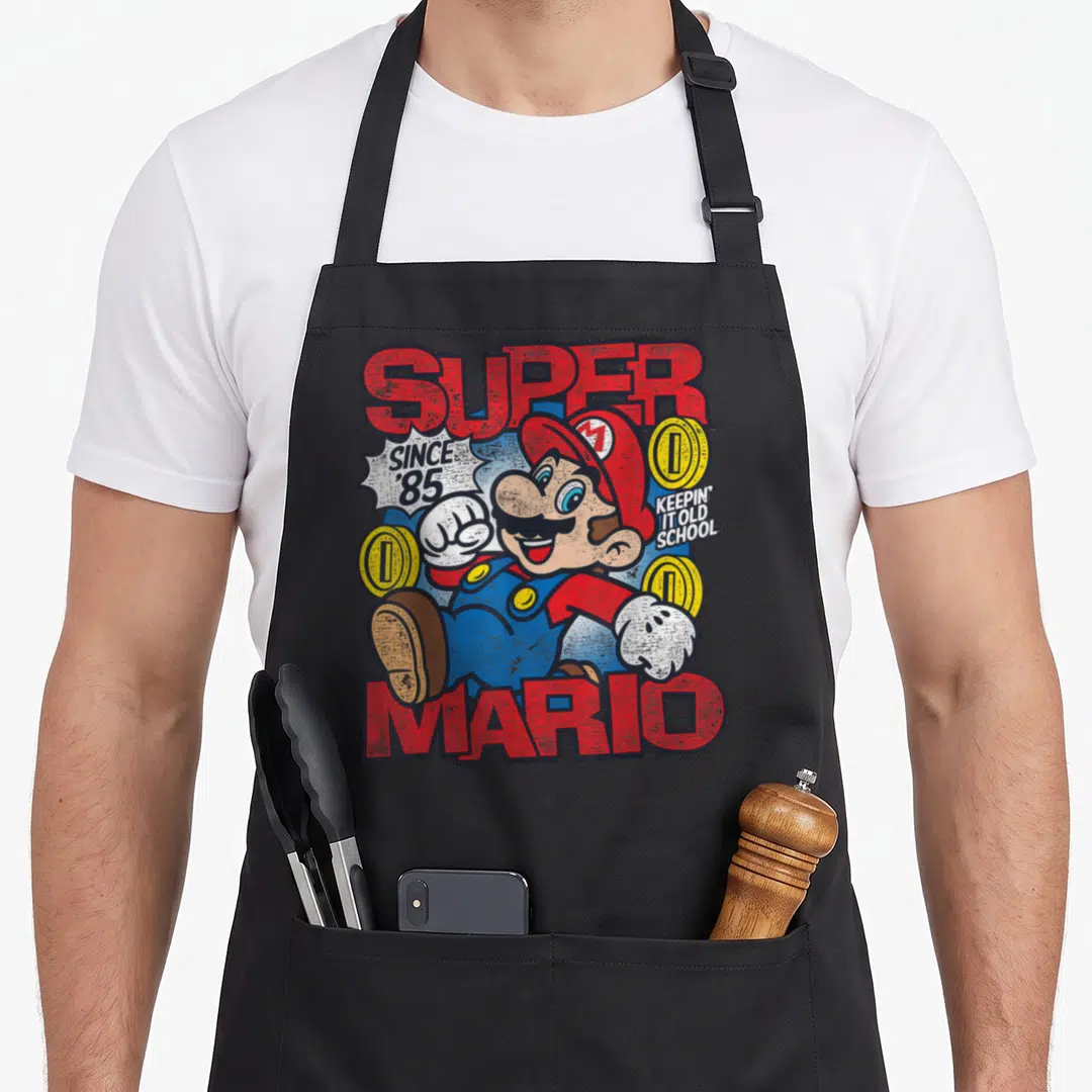 Bro mushroom apron - Distressed Mario graphic with SUPER SINCE '85 text and yellow coins on black fabric — shown on a black cotton canvas apron against a white background
