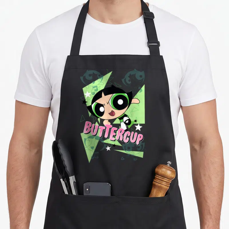 Buttercup cartoon apron - Buttercup character over green triangles and stars with pink text — shown on a black cotton canvas apron against a white background