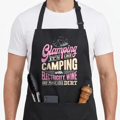 Glamper glamping apron - White tent outline above pink and beige text reading glamping its like camping — shown on a black cotton canvas apron against a white background