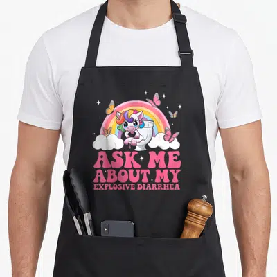 Embarrassing gag aprons - Crying unicorn on toilet with rainbow and ASK ME ABOUT MY EXPLOSIVE DIARRHEA text — shown on a black cotton canvas apron against a white background