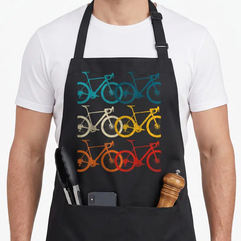 Bike road cycling apron - Six retro bicycles in teal blue beige yellow orange and red arranged in a grid — shown on a black cotton canvas apron against a white background