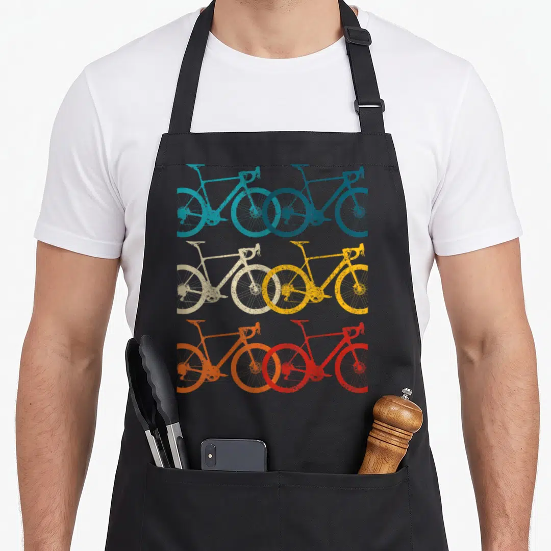 Bike road cycling apron - Six retro bicycles in teal blue beige yellow orange and red arranged in a grid — shown on a black cotton canvas apron against a white background