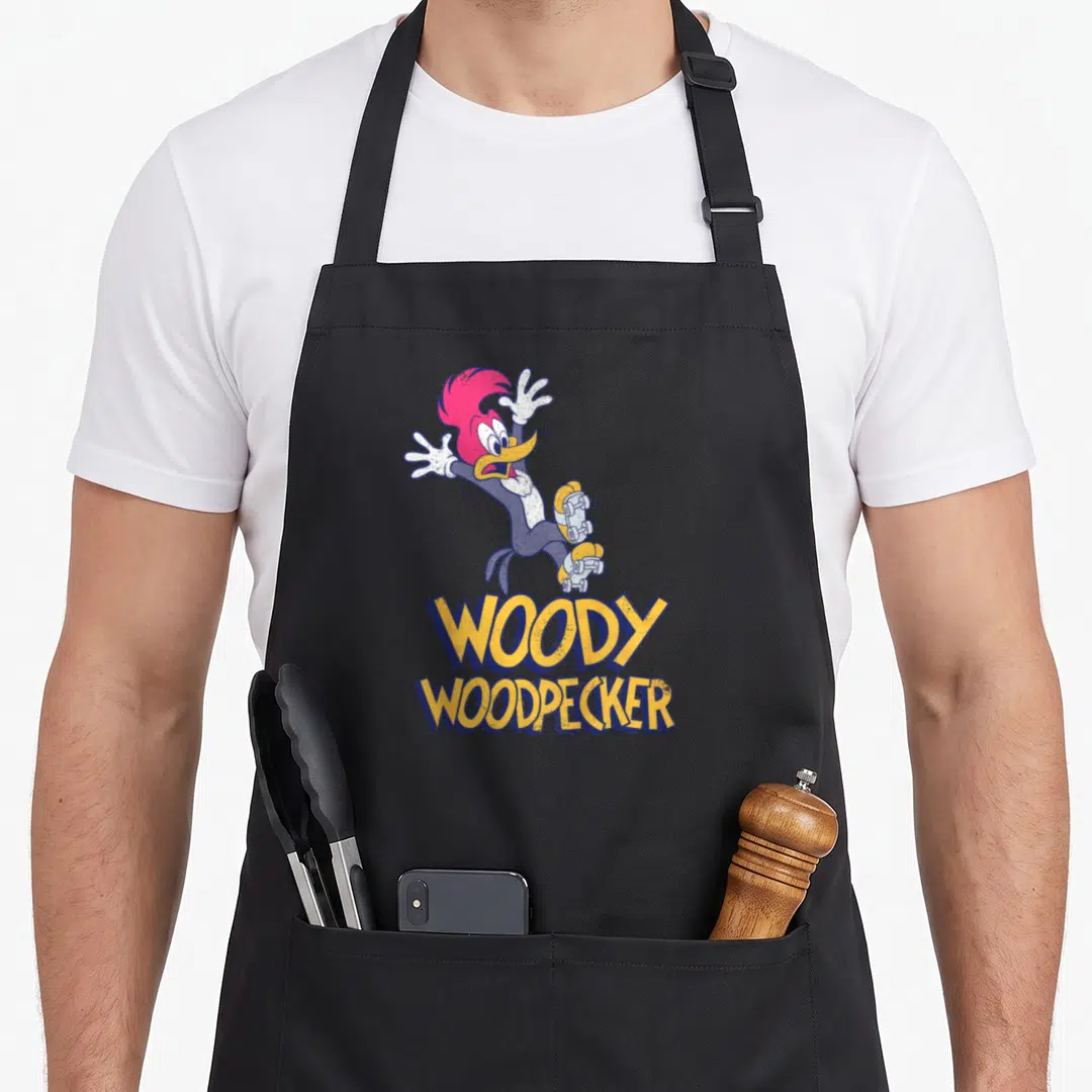 Falling roller skating apron - Woody Woodpecker character on a skateboard with yellow and blue stacked lettering — shown on a black cotton canvas apron against a white background