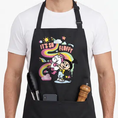 Despicable rainbow apron - Girl hugging unicorn with IT'S SO, FLUFFY text and rainbow background — shown on a black cotton canvas apron against a white background