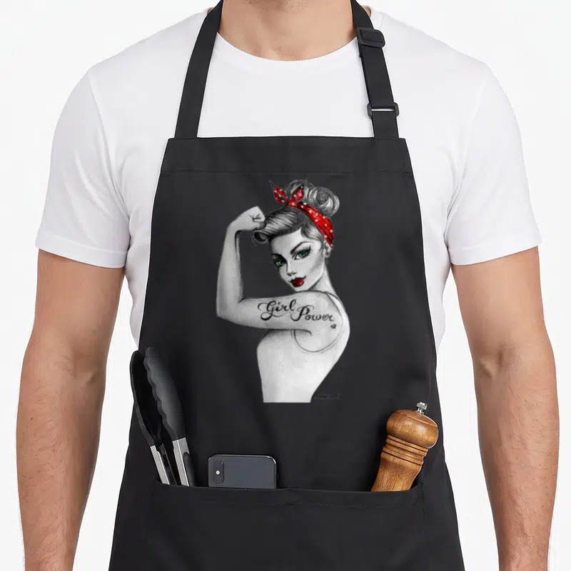 Power rosie the riveter apron - Realistic sketch of a woman flexing arm with Girl Power tattoo in grey white red — shown on a black cotton canvas apron against a white background