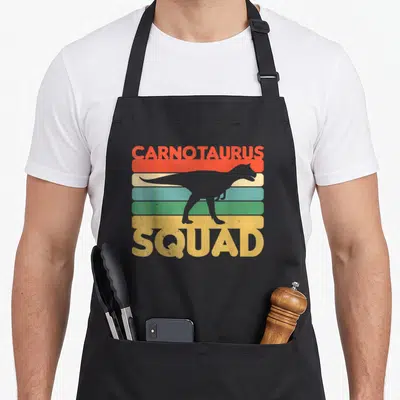 Carnotaurus dinosaur apron - Grey dinosaur silhouette over red yellow blue green grey stripes with CARNOTAURUS SQUAD — shown on a black cotton canvas apron against a white background