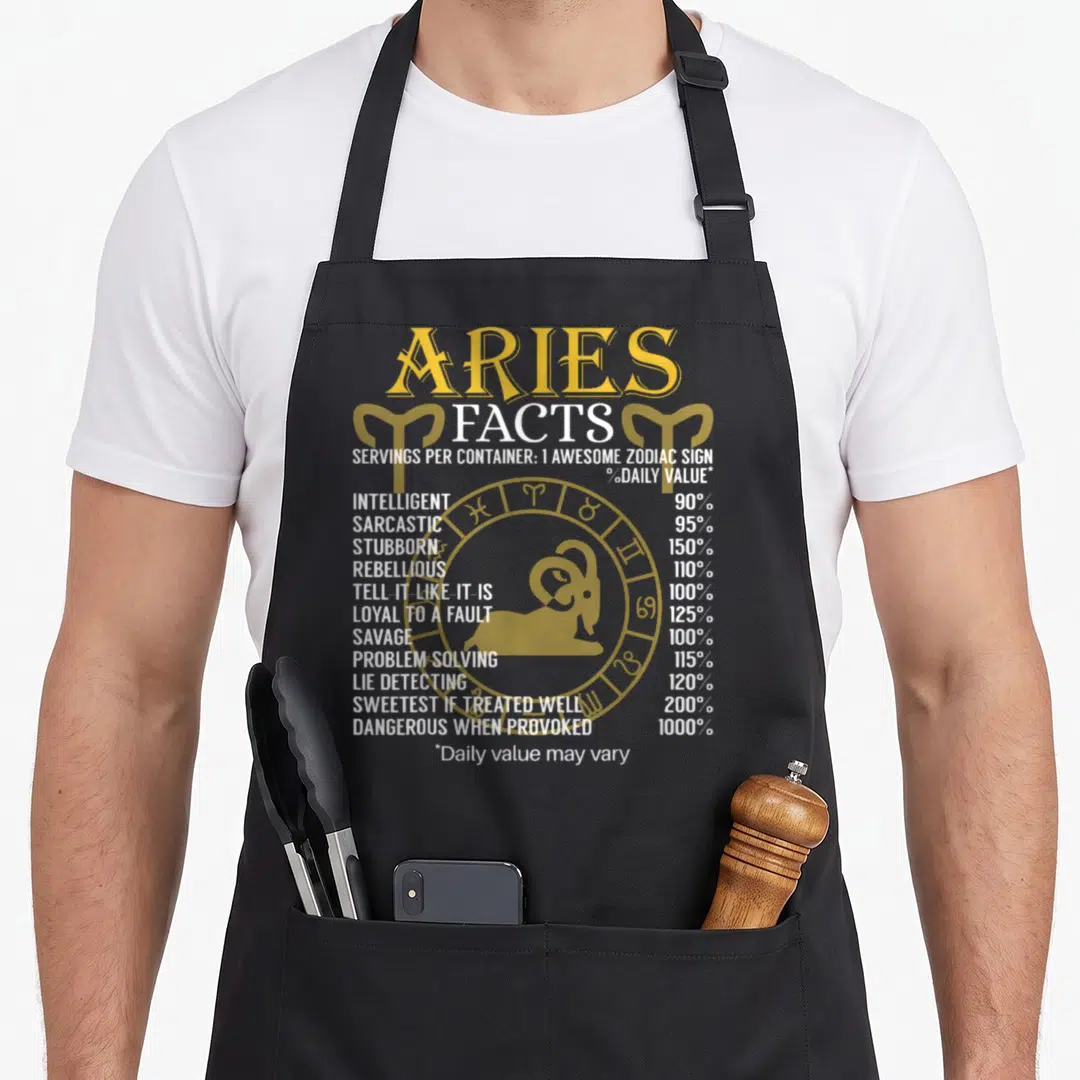 Ary zodiac aprons - Aries Facts nutrition label text with ram illustration and zodiac wheel in yellow and white — shown on a black cotton canvas apron against a white background