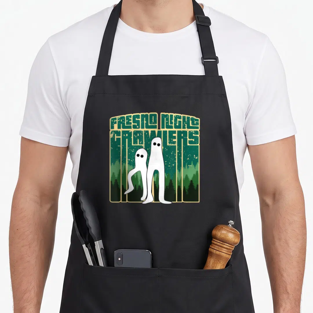 Fresno crawler apron - Two white ghosts standing before green pine forest with FRESNO NIGHT CRAWLERS text in tan border — shown on a black cotton canvas apron against a white background