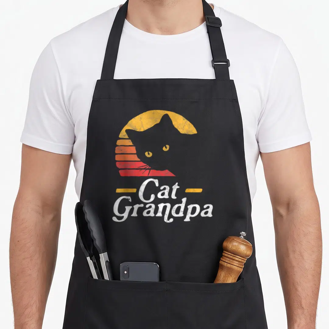 Grandpa cat apron - Retro striped sun behind grey cat silhouette with stacked Cat Grandpa text — shown on a black cotton canvas apron against a white background