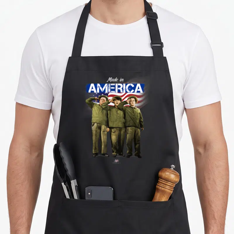 Vtv three stooges apron - Three soldiers in olive uniforms saluting under Made in AMERICA text over flag — shown on a black cotton canvas apron against a white background