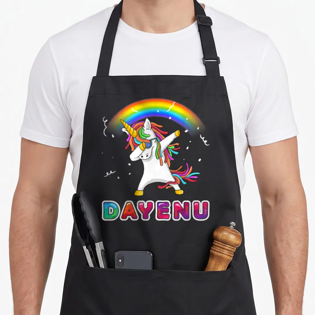 Unicorn passover apron - Dabbing white unicorn with rainbow mane and sunglasses under a rainbow arc above colorful — shown on a black cotton canvas apron against a white background